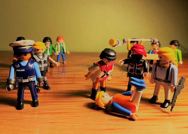 A victim on the ground surrounded by perpetrators and authorities, portrayed by Playmobil figures A victim on the ground surrounded by perpetrators and authorities, portrayed by Playmobil figures
