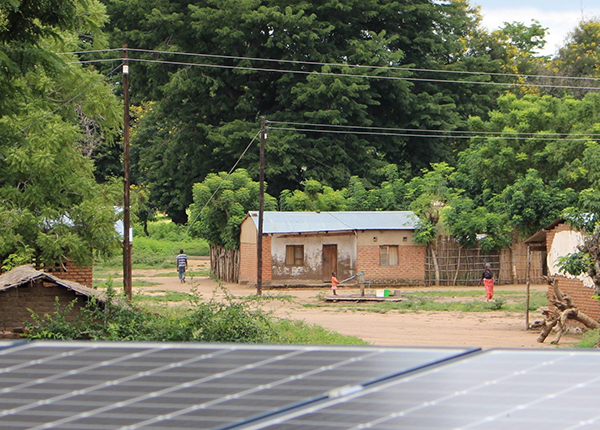 Solar panels in the foreground, small buildings with rooftop solar panels in the background, in Malawi Solar panels in the foreground, small buildings with rooftop solar panels in the background, in Malawi