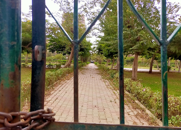 Looking through a chained gate at a neglected city park Looking through a chained gate at a neglected city park