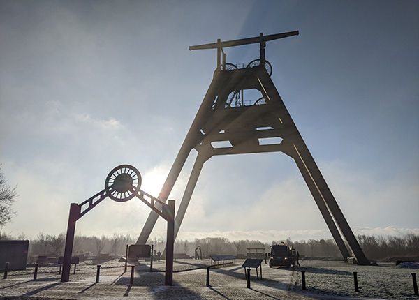A fixed pulley structure on an old mining site with the sun shining through A fixed pulley structure on an old mining site with the sun shining through
