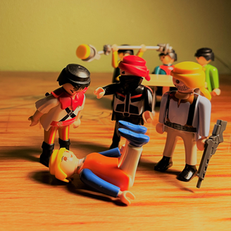 A victim on the ground surrounded by perpetrators and authorities, portrayed by Playmobil figures A victim on the ground surrounded by perpetrators and authorities, portrayed by Playmobil figures