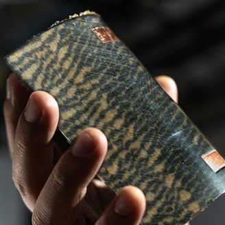 A close up of a hand holding a curved patterned board with two copper rectangles A close up of a hand holding a curved patterned board with two copper rectangles