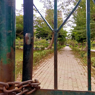 Looking through a chained gate at a neglected city park Looking through a chained gate at a neglected city park