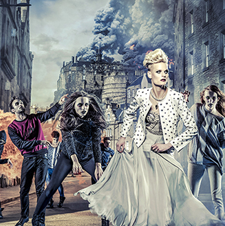 A dressed up woman runs down a street chased by zombie-like people with fire in the background A dressed up woman runs down a street chased by zombie-like people with fire in the background