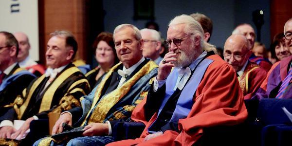 Billy Connelly seated at graduation ceremony
