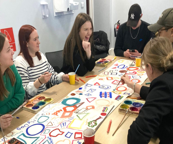 Group of people round a table with colourful drawings on it