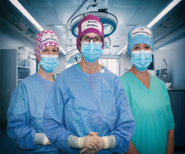 Group of 3 people wearing theatre scrubs and hat