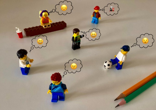 Lego figures playing games with emojis above their heads