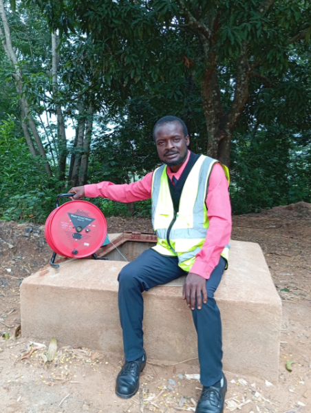 Man sitting on a well with hi vis vest on and measuring device