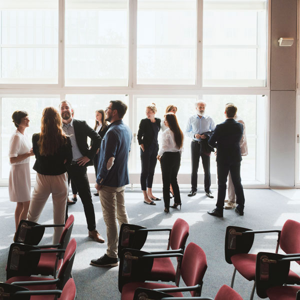 a group of people stand up chatting with each other a group of people stand up chatting with each other
