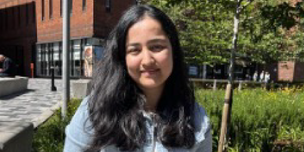 Ayushi sitting outside on campus on a sunny day